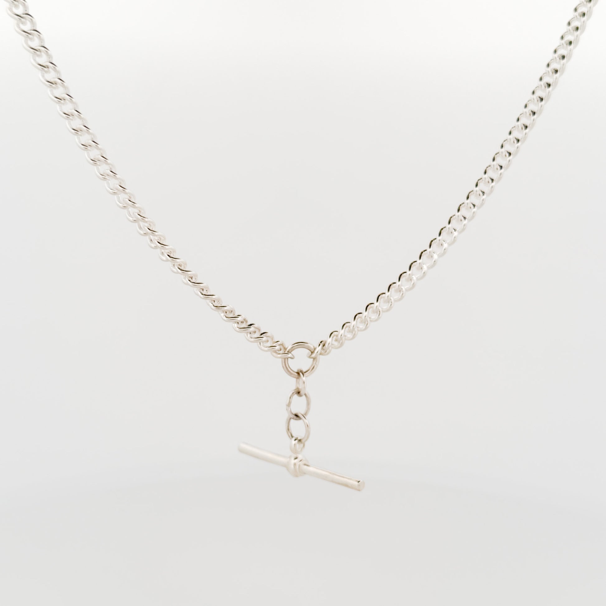 Silver necklace with a clasp on a light gray background