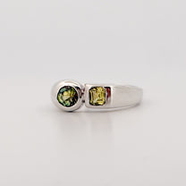 Silver ring with green gemstones on a light gray background