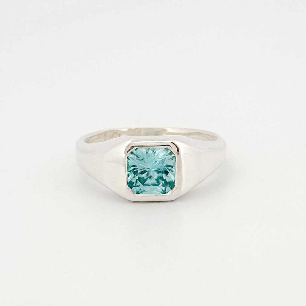 Silver ring with a square-cut blue gemstone on a white background