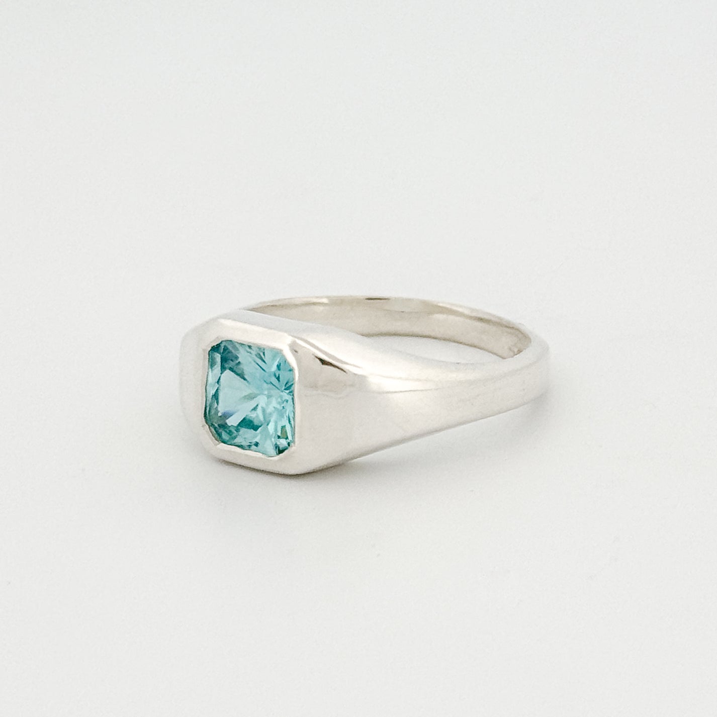 Silver ring with a blue gemstone on a light gray background