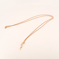 Gold necklace with a delicate pendant on a light beige background
