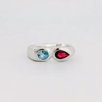 Silver ring with a blue gem and a red gem on a light gray background