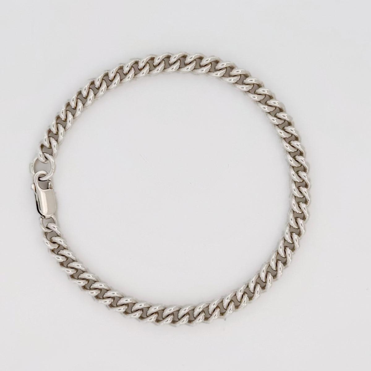 CASPER wrist chain in sterling silver, curb links, laid in a circle.