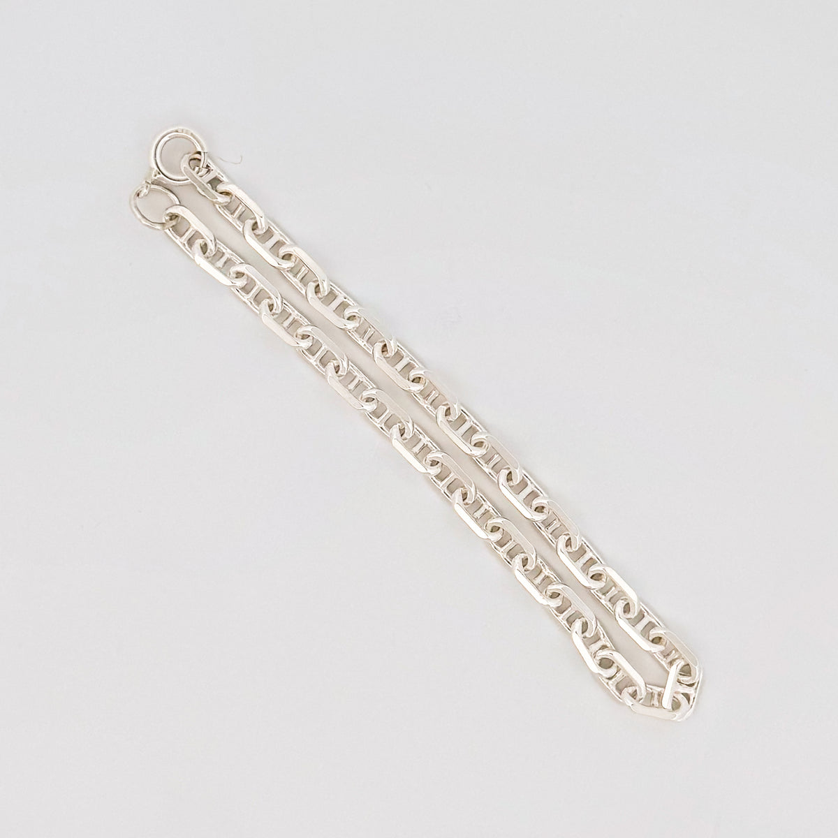 MARINER chain in sterling silver, angular mariner links, folded in a flat lay. Italian-made for AGOVIA.